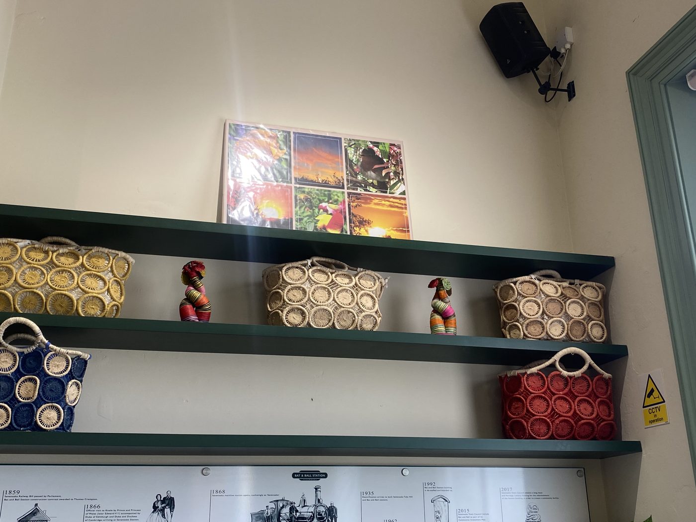 Handwoven baskets in yellow, blue, red and natural straw lined along sage-green shelves