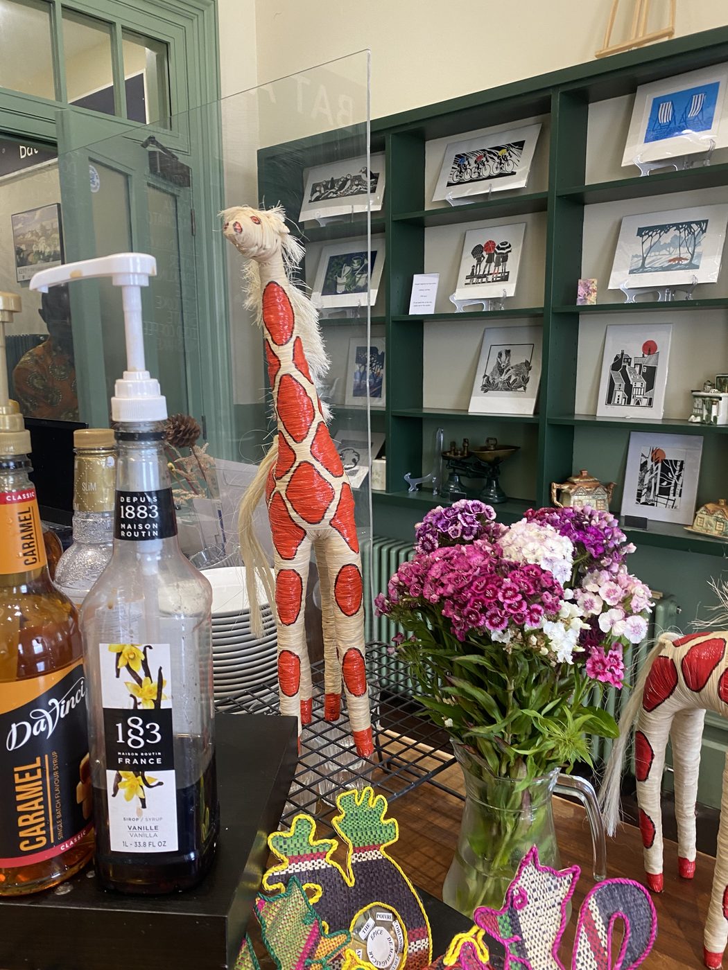 The makers' shelf with woven crafts, fresh flowers and coffee syrups