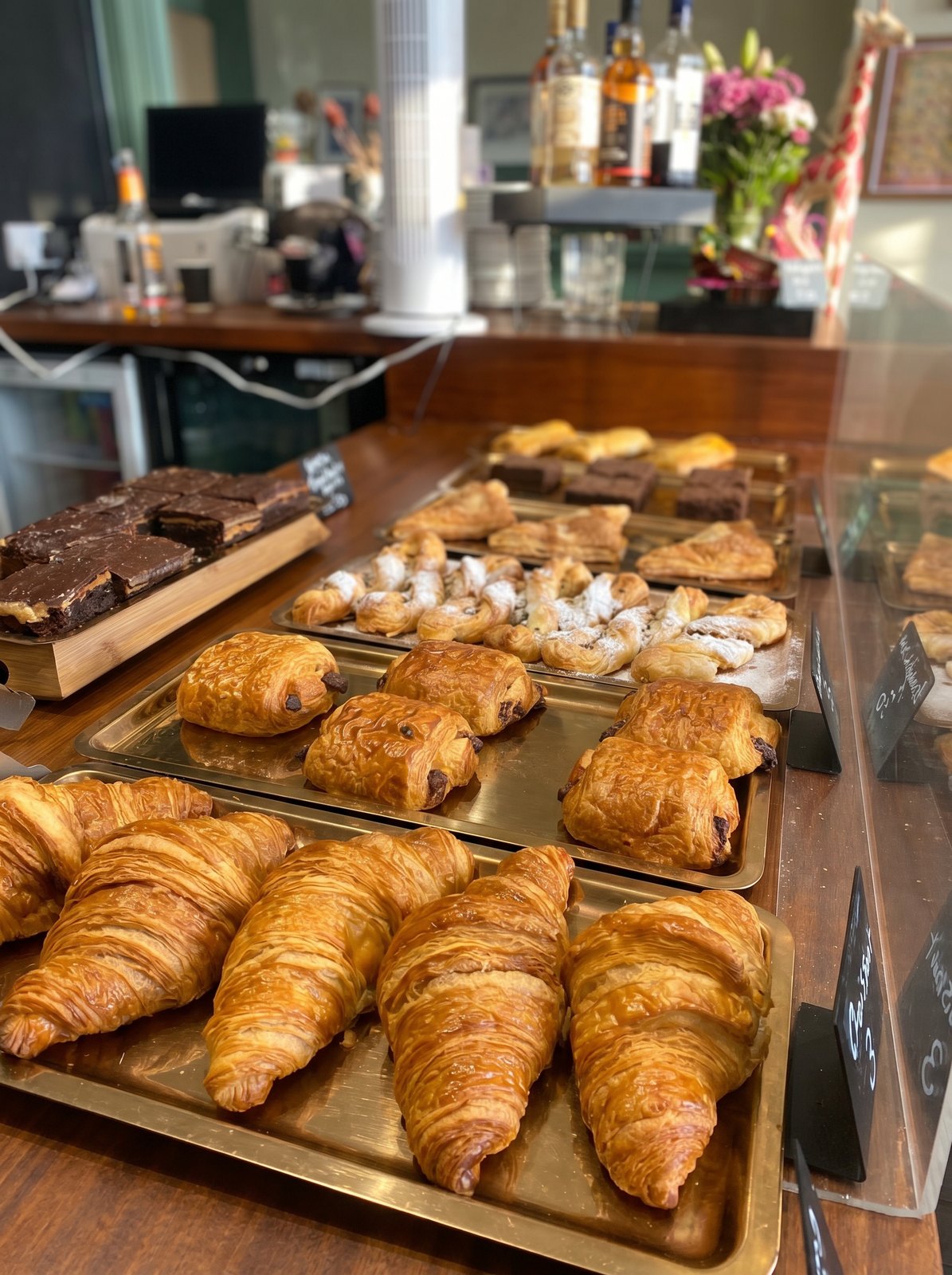 Trays of fresh croissants, pain au chocolat, almond croissants and brownies on the café counter